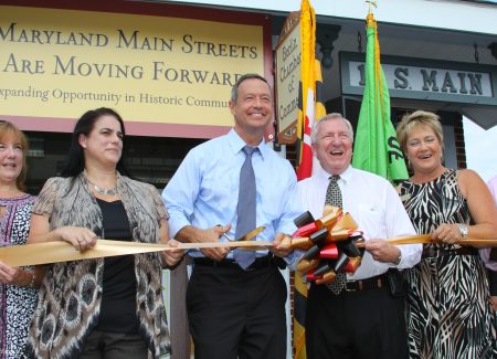 a group of people holding a ribbon in front of a building