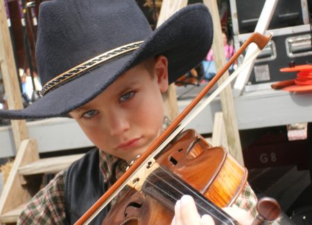 a young boy wearing a cowboy hat playing a violin