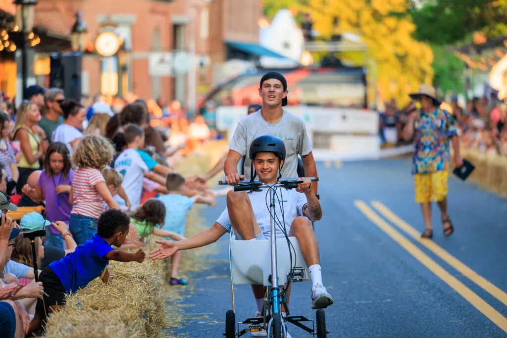 a man riding a bike down a street next to a crowd of people